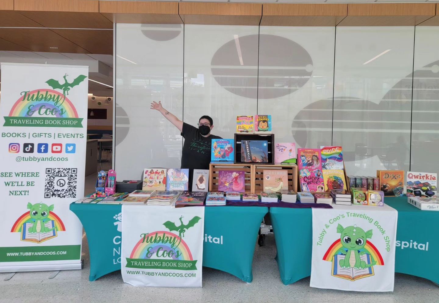 Tubby & Coo's owner, Candice Huber, stands behind a table full of books.